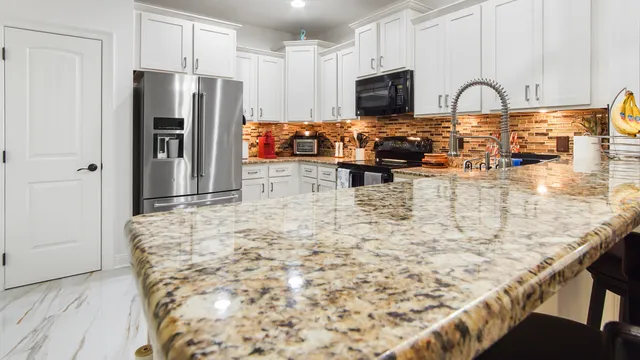 a view of kitchen with stainless steel appliances granite countertop a refrigerator and a stove top oven