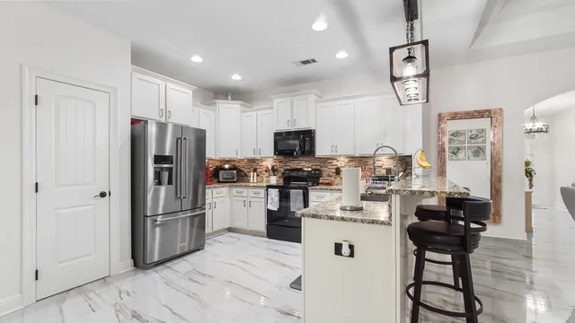 a kitchen with stainless steel appliances kitchen island granite countertop a refrigerator and a stove top oven