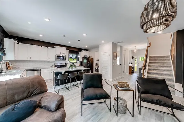 a living room with stainless steel appliances kitchen island granite countertop furniture and a large window