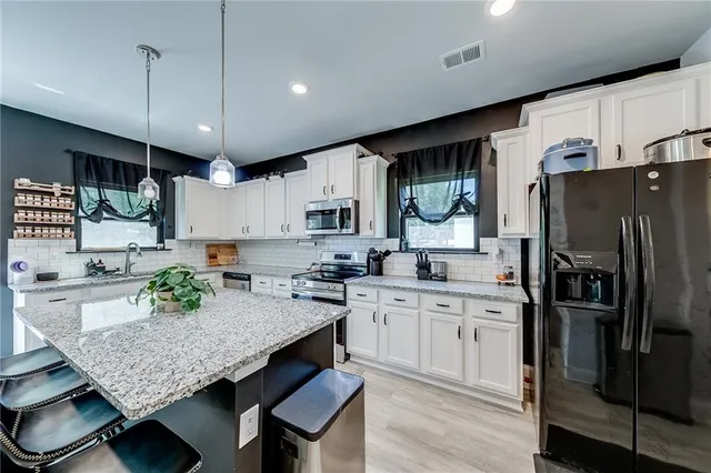 a kitchen with granite countertop a table chairs stove and refrigerator