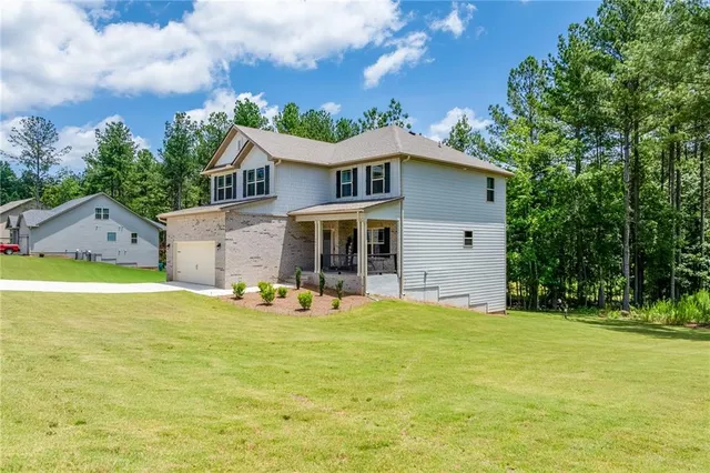 a front view of house with yard and trees in the background