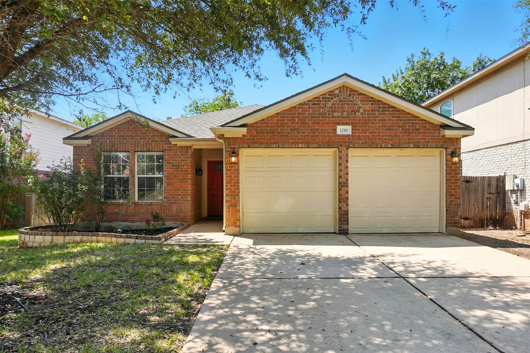 Ranch-style home featuring an attached garage, concrete driveway, a shingled roof, and brick siding