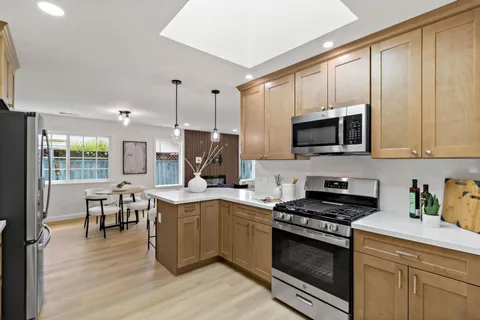 a kitchen with stainless steel appliances kitchen island granite countertop a dining table chairs and view living room