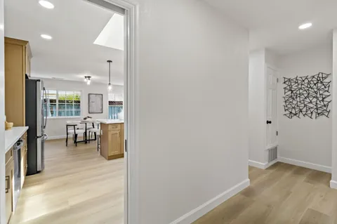 a view of a hallway with wooden floor and a living room