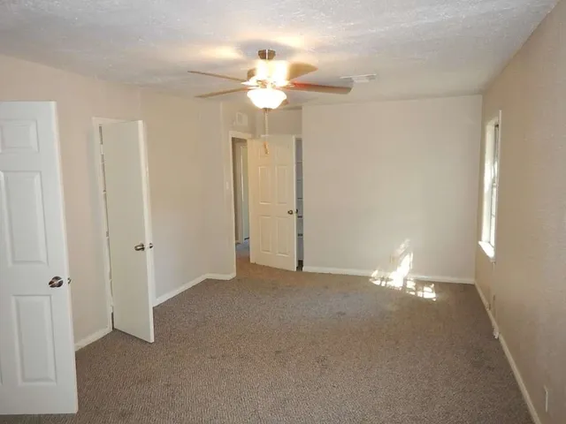 a view of an empty room with a chandelier fan