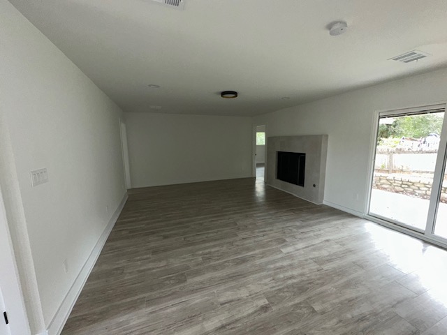 2101 Vanderbilt Lane Austin, TX 78723 - Photo 4 of 11 Unfurnished living room with light wood-type flooring, plenty of natural light, and a fireplace