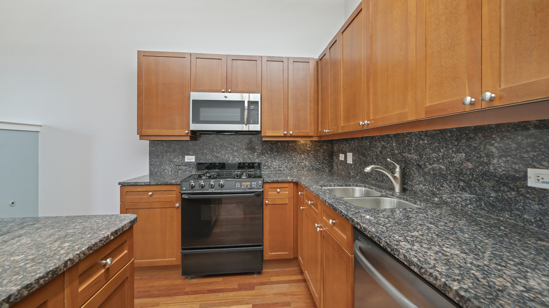 1301 West Madison Street, Unit 304 Chicago, IL 60607 - Photo 7 of 15 a kitchen with stainless steel appliances granite countertop wooden cabinets a stove and a sink