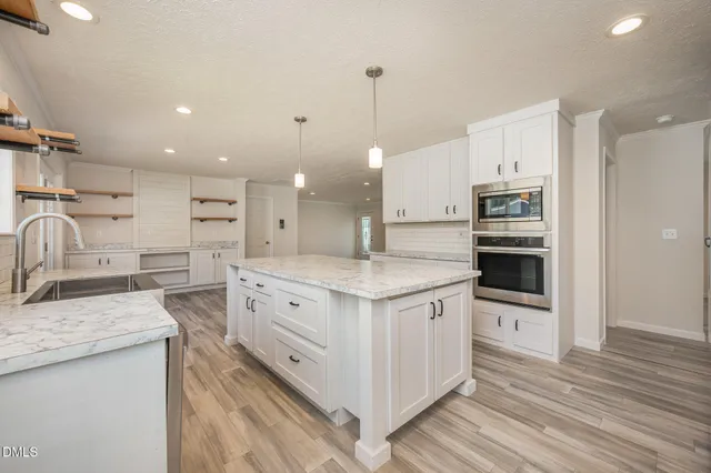 a kitchen with stainless steel appliances kitchen island granite countertop a sink and a stove top oven