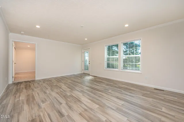 an empty room with wooden floor and windows