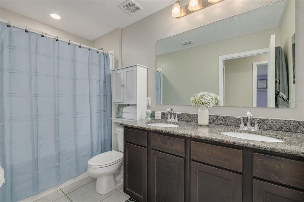 7242 Landmark Drive Spring Hill, FL 34606 - Photo 35 of 45 a bathroom with a granite countertop sink a toilet a mirror and shower curtain