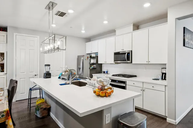 a kitchen that has a lot of cabinets a sink and appliances