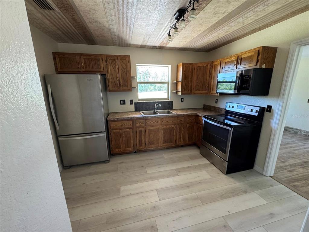 a kitchen with stainless steel appliances granite countertop a stove a refrigerator a sink dishwasher a refrigerator and a microwave oven