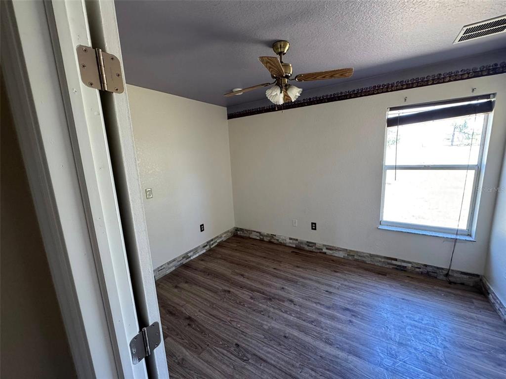 14373 Irving Street Spring Hill, FL 34609 - Photo 2 of 4 a view of an empty room with wooden floor and a window