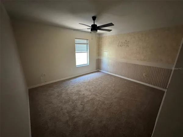 an empty room with windows and fan