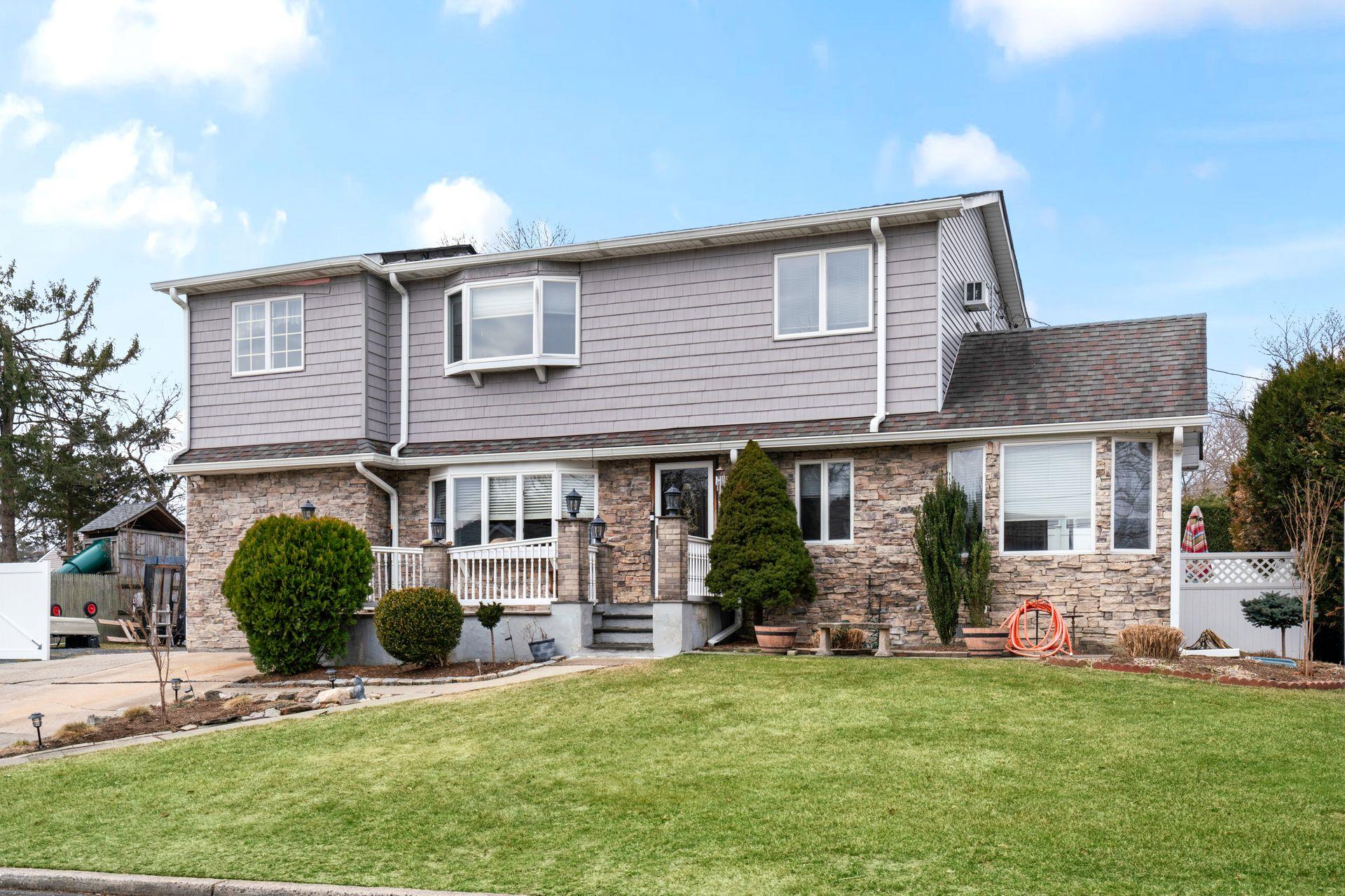 5 Sun Haven Lane Commack, NY 11725 - Photo 1 of 1 View of front of house featuring stone siding, a shingled roof, and a front lawn