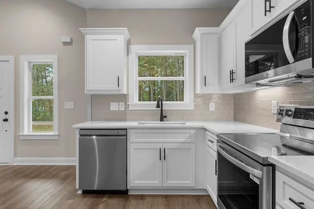 a kitchen with stainless steel appliances granite countertop a sink a stove a microwave and wooden cabinets