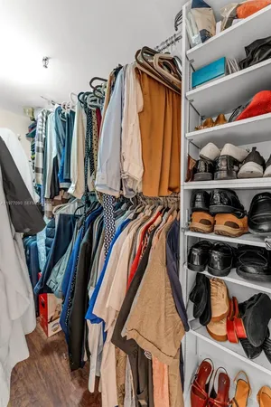 a view of walk in closet with clothes and shoes