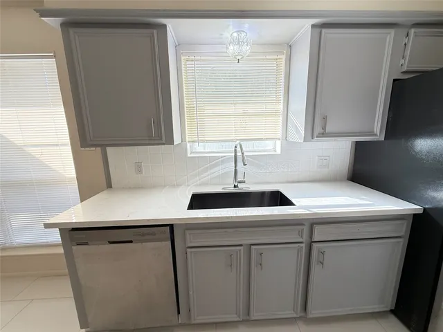 a kitchen with white cabinets sink and window