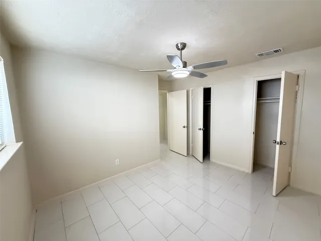 an empty room with windows and fan