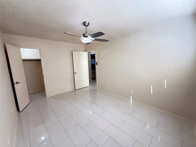 an empty room with chandelier fan and windows