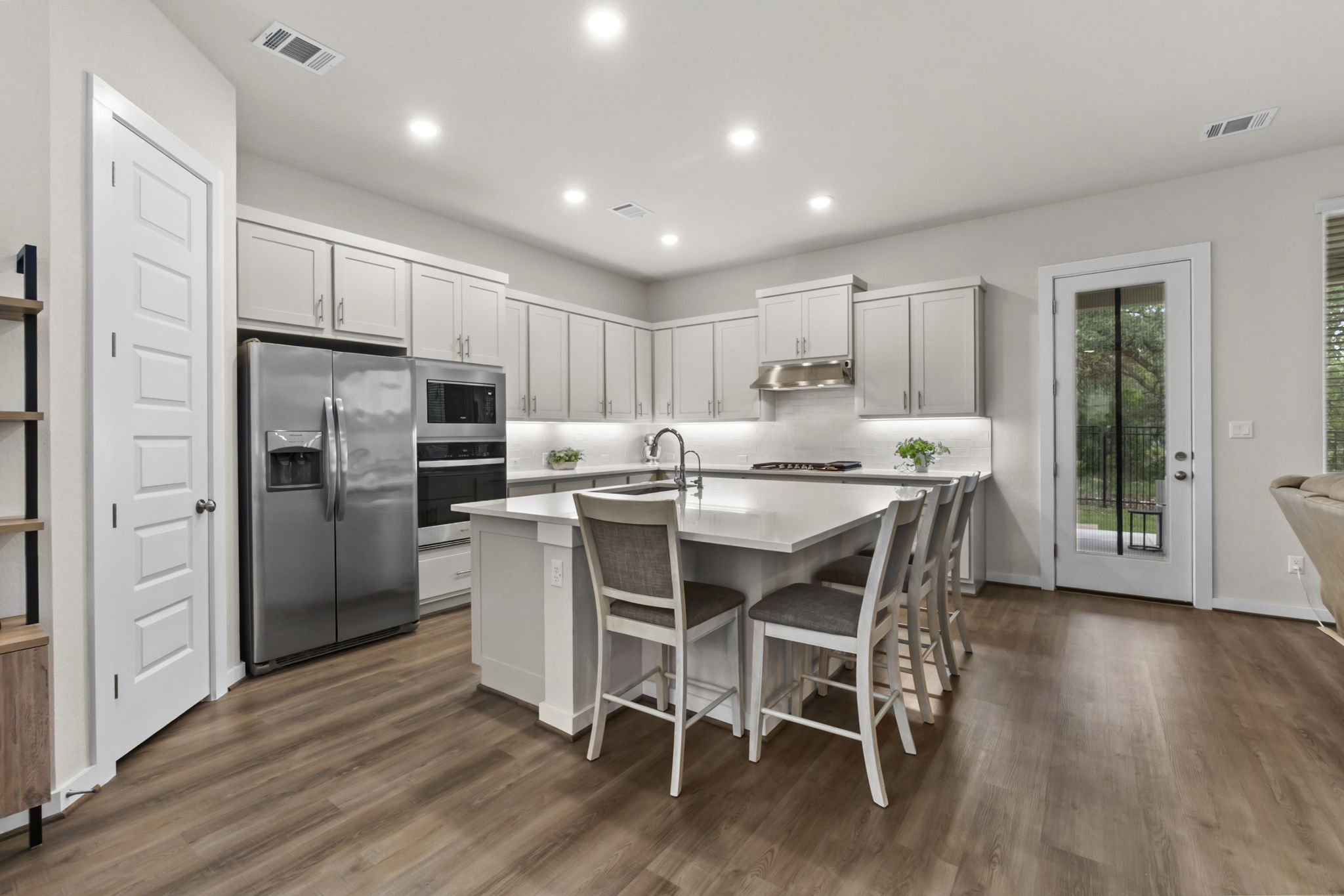 460 Constitution Way Kyle, TX 78640 - Photo 14 of 40 Open-concept kitchen featuring an oversized central island with seating, stainless steel appliances, light gray cabinetry, recessed lighting, and wood-finish flooring