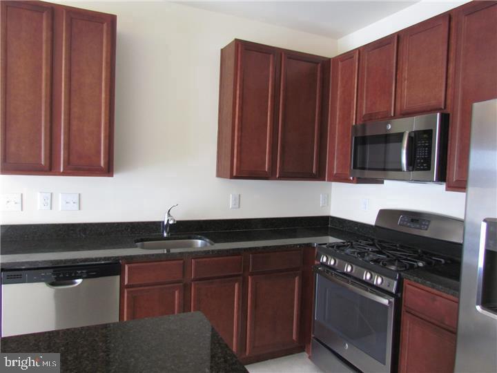 3889 Cephas Child Road, Unit 13 Doylestown, PA 18902 - Photo 10 of 25 a kitchen with granite countertop wooden cabinets and black stove top oven