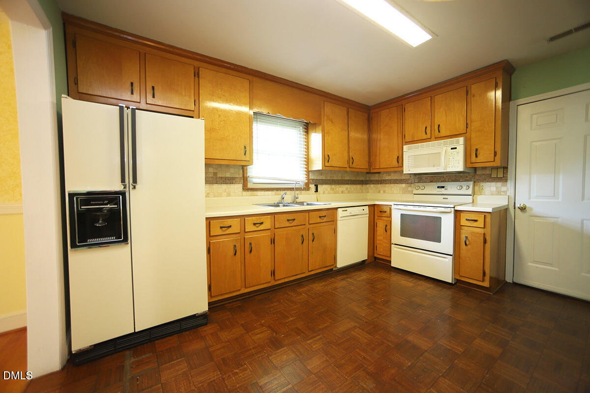 3518 Randolph Road Durham, NC 27705 - Photo 19 of 32 a kitchen with stainless steel appliances granite countertop a stove a sink dishwasher a refrigerator and white cabinets with wooden floor