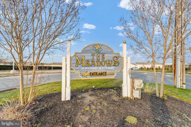 a view of a park that has a sign board large trees