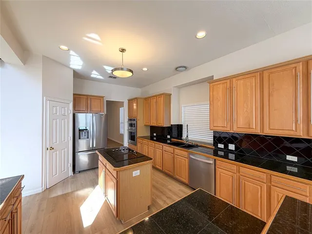 a kitchen with stainless steel appliances a stove a sink a refrigerator a counter top space and cabinets