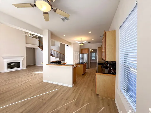 a living room with stainless steel appliances furniture wooden floor and a kitchen view