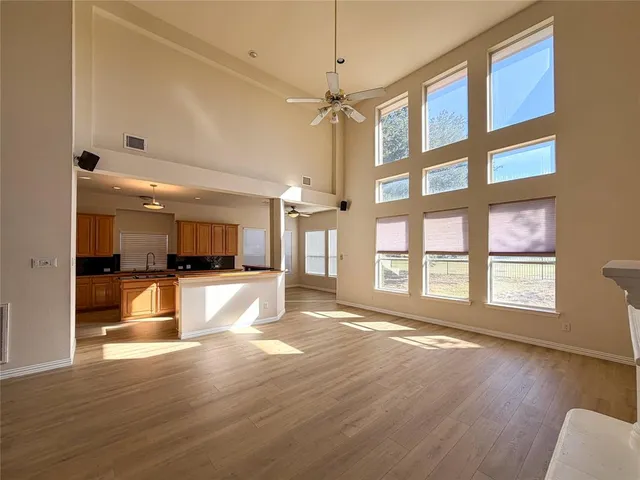a view of a living room kitchen with a large window a wooden floor and a sink