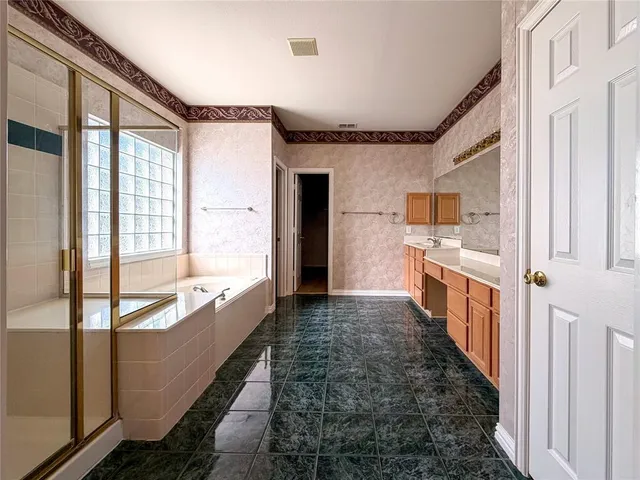 a large white kitchen with stainless steel appliances kitchen island granite countertop a refrigerator a stove and a sink with wooden cabinets