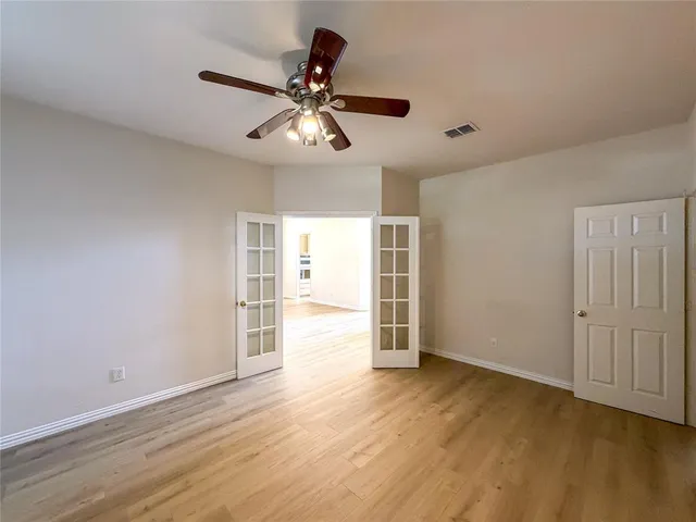 a view of empty room with wooden floor and ceiling fan