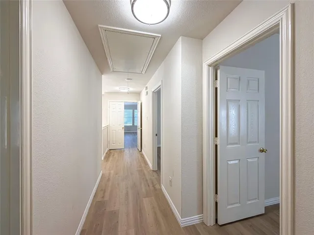 a view of a hallway with wooden floor and a bathroom