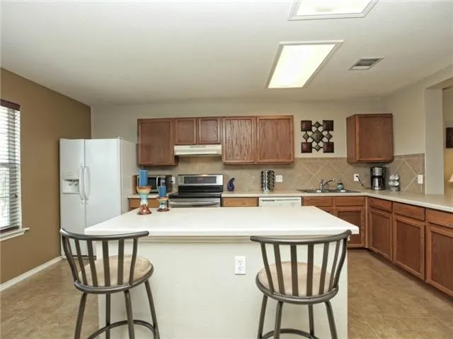a kitchen with stainless steel appliances a dining table chairs microwave and sink