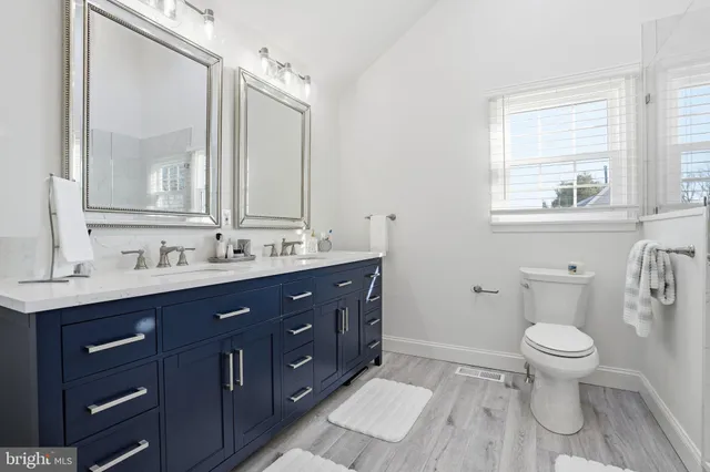 a bathroom with a toilet sink double vanity and mirror