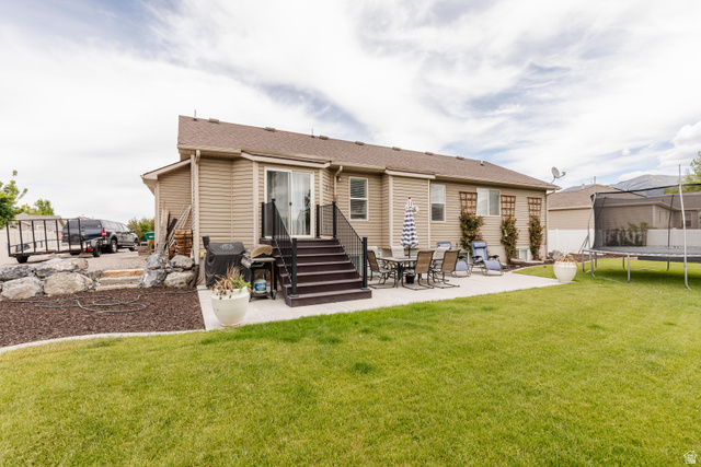 972 West 2840th Street South Logan, UT 84321 - Photo 35 of 46 Expansive backyard featuring a manicured lawn, a large concrete patio, and a multi-level deck with black railings