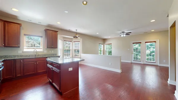 a large kitchen with stainless steel appliances granite countertop a large stove a sink dishwasher and a large island with wooden floor