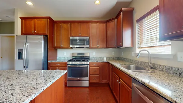 a kitchen with stainless steel appliances granite countertop a sink stove and refrigerator