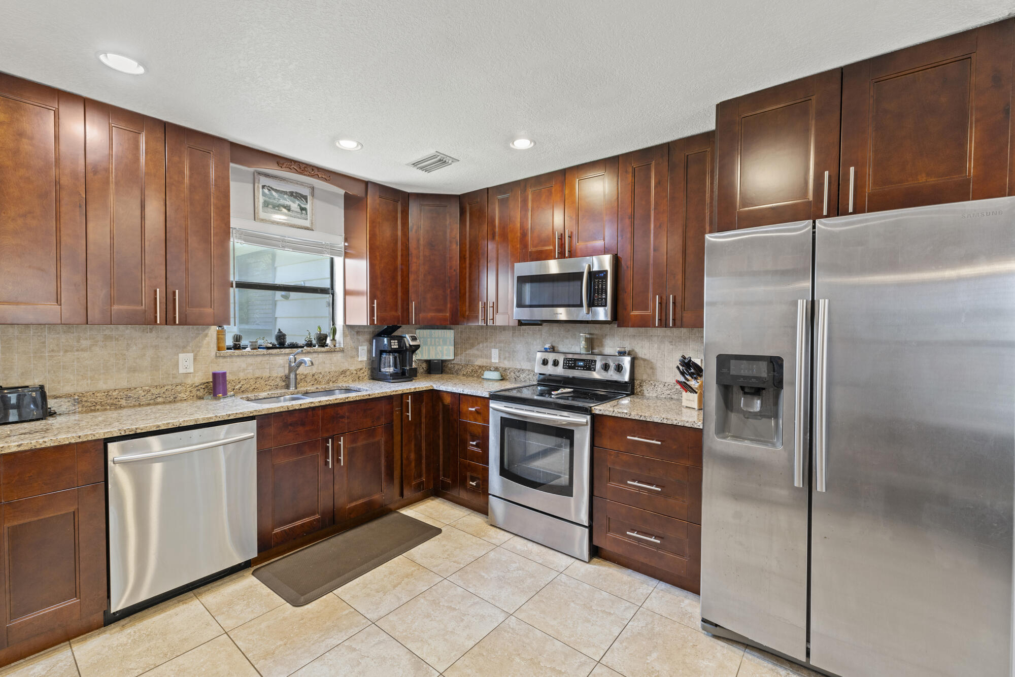 591 Kriss Lane Jupiter, FL 33458 - Photo 11 of 36 a kitchen with stainless steel appliances granite countertop wooden cabinets a stove top oven a sink and dishwasher