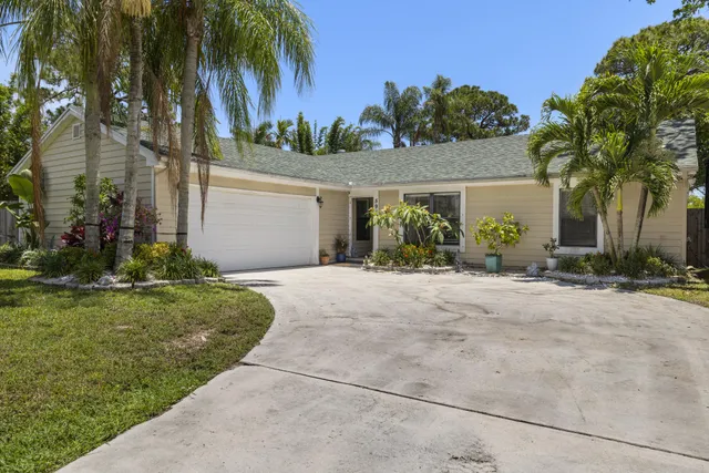 front view of house with a yard and palm trees