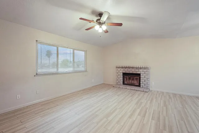 a view of an empty room with wooden floor and a fireplace