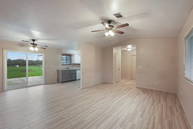 a view of an empty room with a kitchen and wooden floor