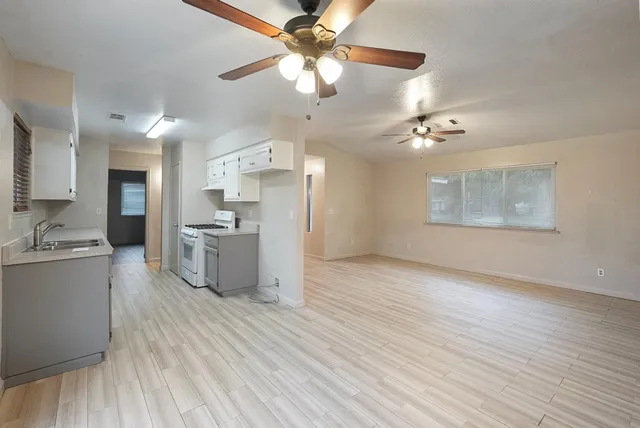 a view of a kitchen with a sink cabinets wooden floor and a ceiling fan