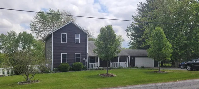 a brick house with a big yard and large trees