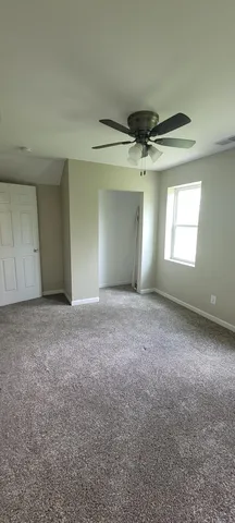 an empty room with windows and ceiling fan