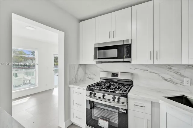 a kitchen with stainless steel appliances granite countertop white cabinets and a stove