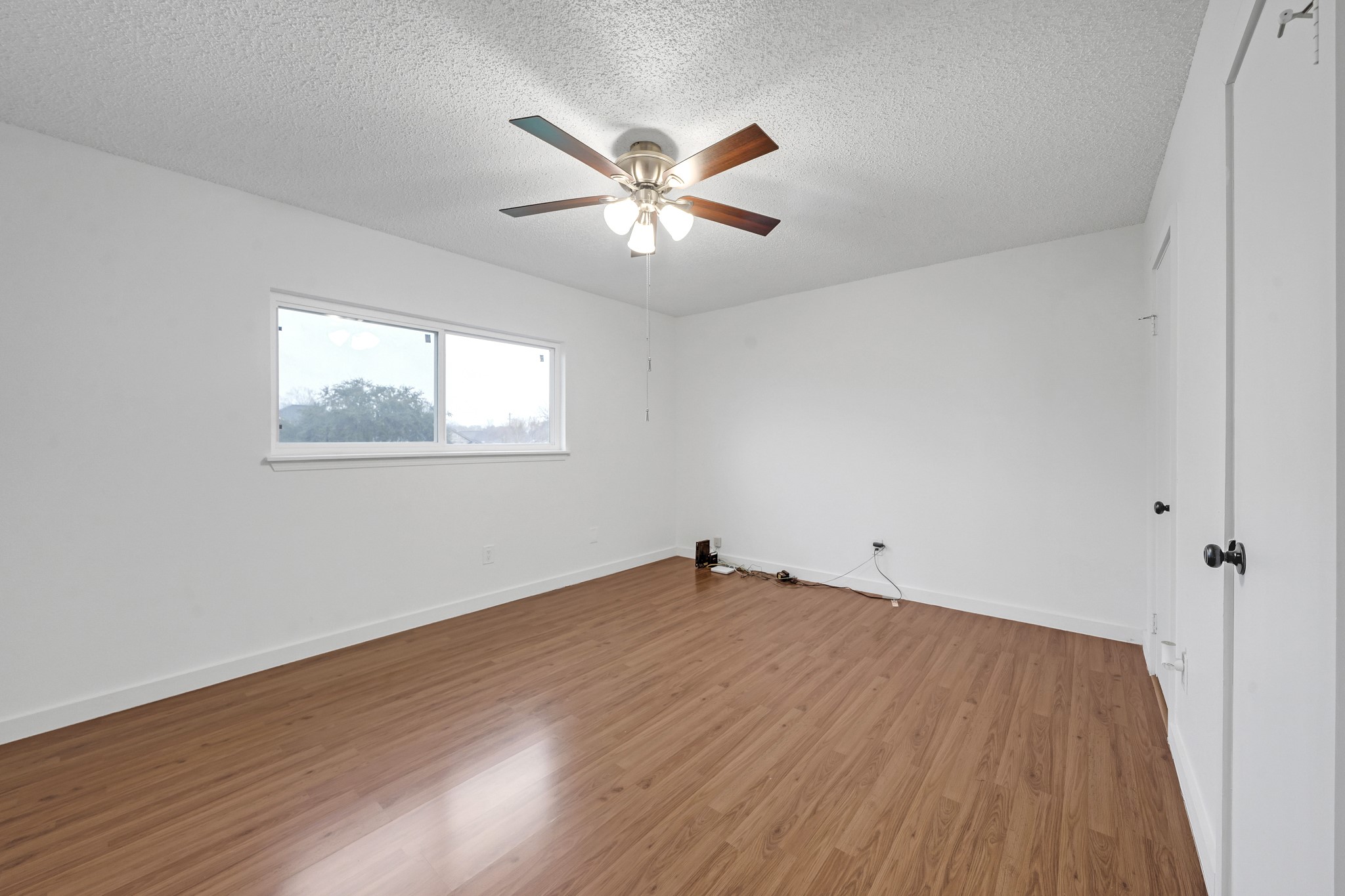 635 Walston Lane Houston, TX 77060 - Photo 15 of 24 This room features a clean, bright space with white walls, a ceiling fan with lights, and wood laminate flooring. A large window provides natural light, and there's a closet on one side.