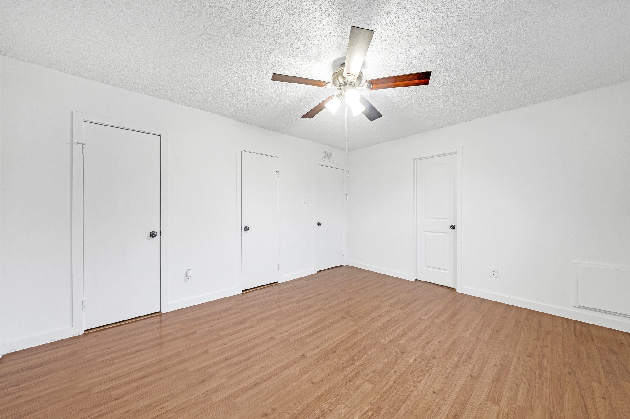 635 Walston Lane Houston, TX 77060 - Photo 16 of 24 This room features hardwood flooring, a ceiling fan with lights, and three white doors, offering a clean and versatile space.