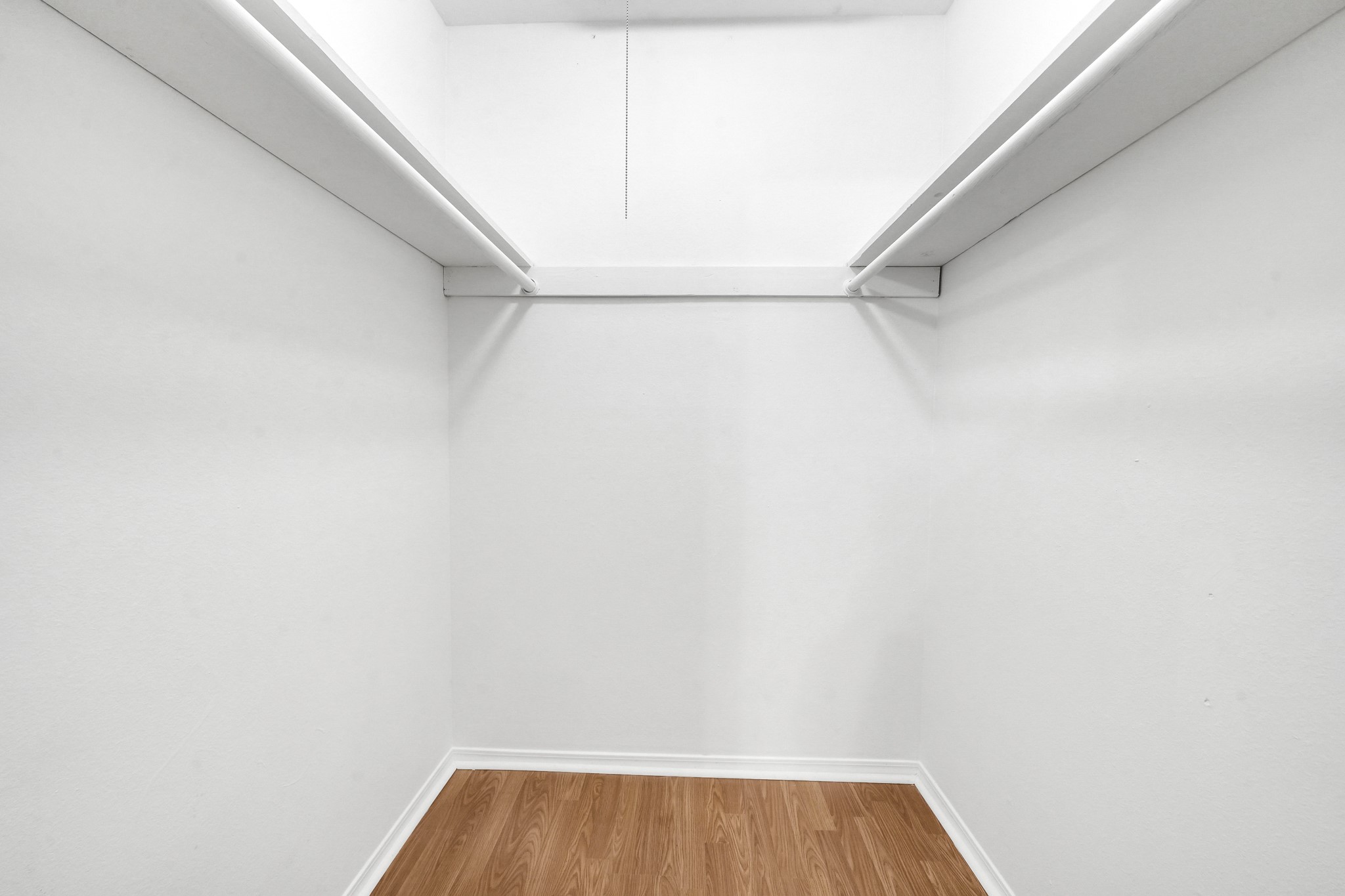635 Walston Lane Houston, TX 77060 - Photo 17 of 24 Spacious walk-in closet with white walls, two hanging rods, and a wood-patterned floor. Perfect for organizing clothes and accessories.